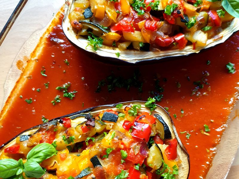 Cooked stuffed eggplant with fresh vegetables in tomato sauce