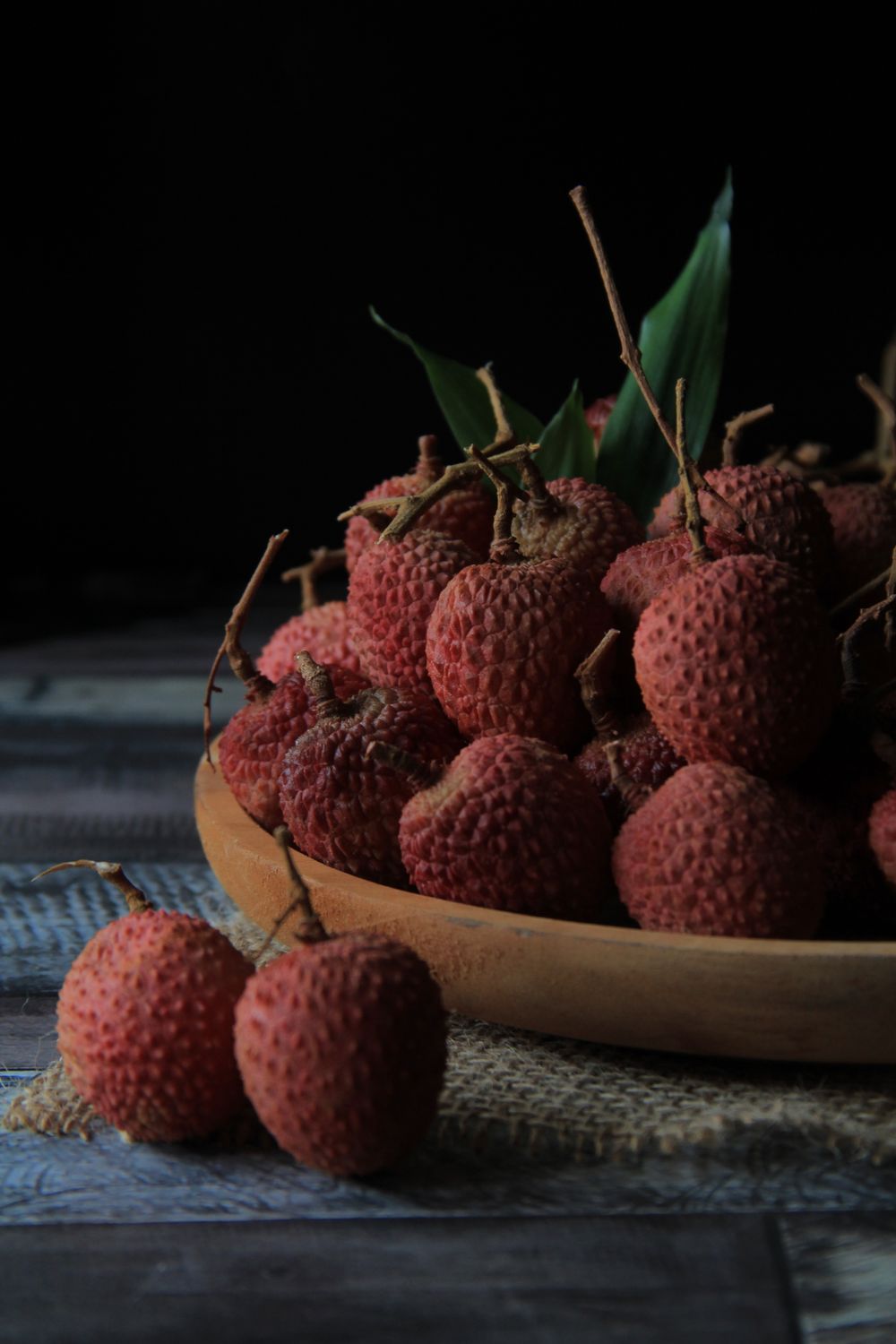 Fresh lychee fruits with red bumpy skin on a plate